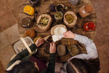 High angle view of shop assistant putting flour into paper bag for customer at zero waste shop.