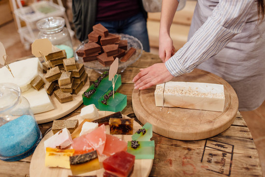 Shop Assistant Cutting Bars Of Natural Soap For Customer In Package Free Store.