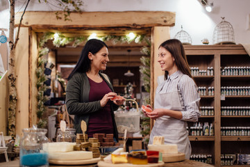 Cheerful shopkeeper helping customer in packaging free shop. Zero waste shopping - woman buying...