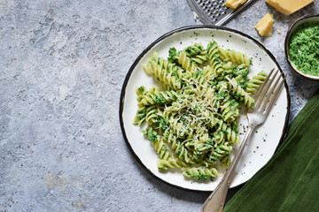 Rotini pasta with parmesan and spinach sauce on a concrete background. Food background. Top view.