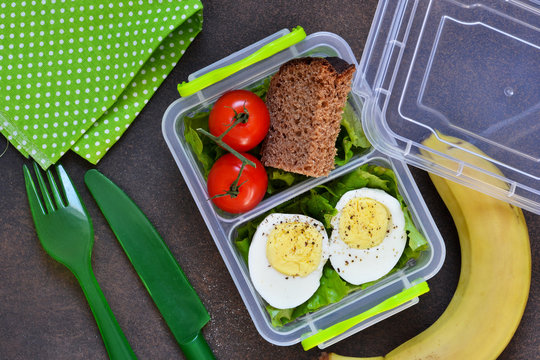 Lunch box with egg, tomato, salad and sandwich. View from above.