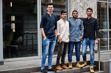 Group of four indian mans, wear on casual clothes, posed outdoor at street of India.