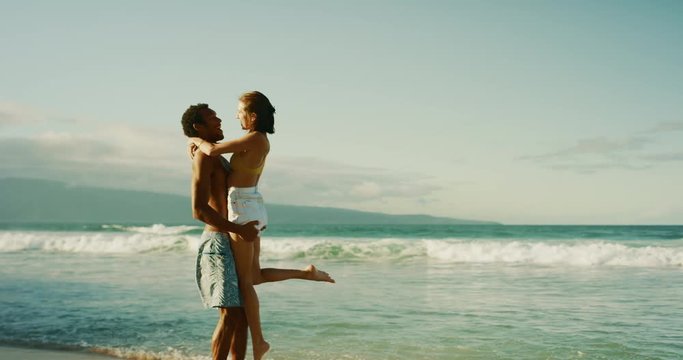 Adorable girlfriend leaping into her strong boyfriend's arms on a gorgeous beach