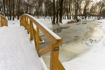 Unmoving frozen river underneath wooden bridge