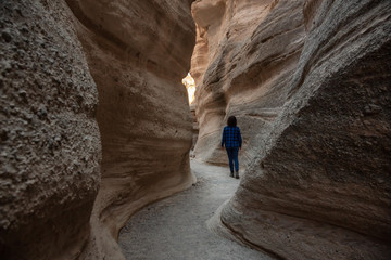 Woman hiking in the Beautiful American Canyon Landscape during a sunny evening. Taken in Kasha-Katuwe Tent Rocks National Monument, New Mexico, United States.