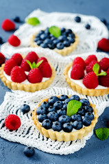 Raspberry and blueberry tartlets with fresh berries and mint leaves