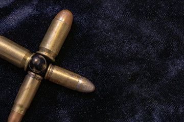 Pistol bullets gathered together in the shape of a cross. War concept. Dark background shot.