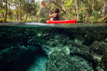 Over and Under picture of a girl kayaking in a lake near an underwater cave formation. Taken in 7...