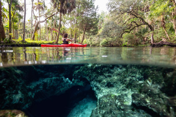 Over and Under picture of a girl kayaking in a lake near an underwater cave formation. Taken in 7...