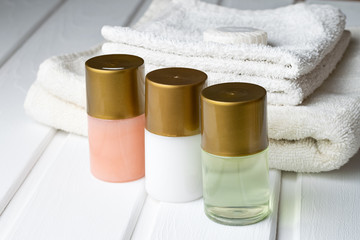 Naklejka premium Tubes of shampoo shower gel and lotion with towels on the table