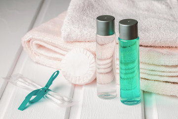 Towels and shampoo with shower gel and soap with cotton buds on the table