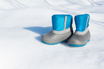 Pair of waterproof children boots on the snow, space for text