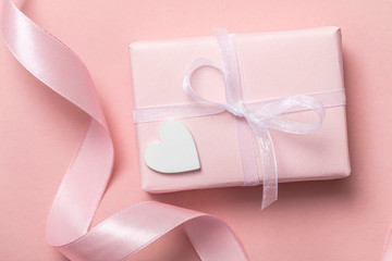 Pink valentine gift with white hearts on a pastel pink background
