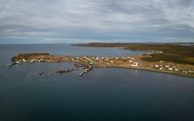 Aerial panoramic view of a small town on a rocky Atlantic Ocean Coast during a cloudy day. Taken in Raleigh, Newfoundland, Canada.