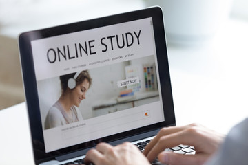 Close up man using laptop, browsing distance learning website, typing on keyboard, student...
