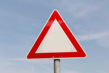 blank warning road sign against blue sky