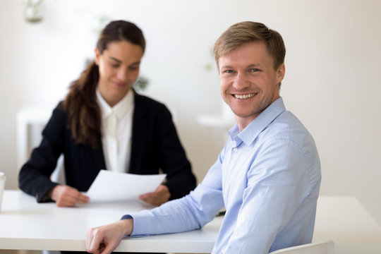 Head shot portrait of smiling male applicant, job seeker at successful job interview, looking at camera, female satisfied hr manager, employer reading resume, hiring concept, staff recruiting process