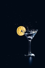 Cocktail water drink splash in the glass with lemon Isolated on black