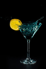 Blue cocktail water drink splash in the glass with lemon Isolated on black