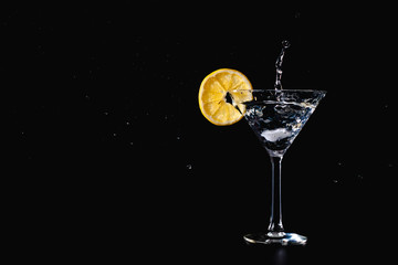 Cocktail water drink splash in the glass with lemon Isolated on black