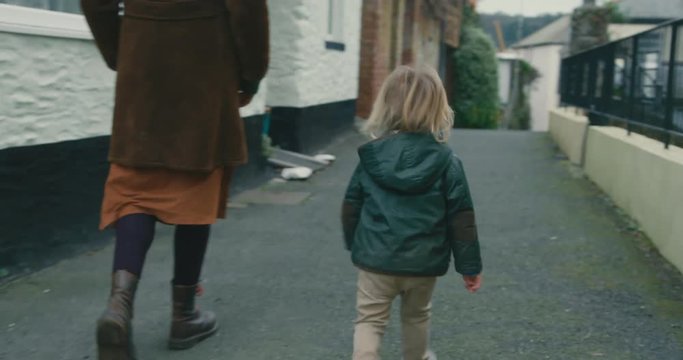 Toddler walking with his mother in small town