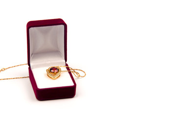 Gold heart pendant with precious stones in a red gift box on white background isolated