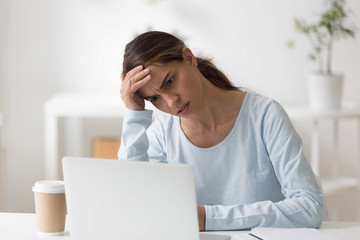 Frustrated woman using laptop, worried about problem, reading bad news online, looking at computer...