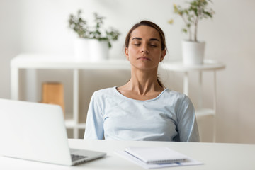 Calm attractive woman relaxing at workplace, sitting with closed eyes, leaning back in chair, meditating at work, deep breath, no stress concept, businesswoman, student resting after finish work
