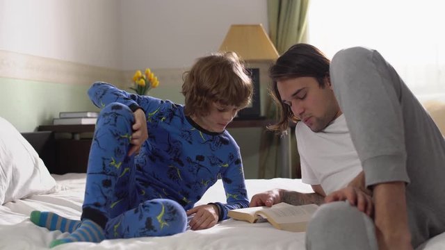 Older and younger brothers in pajamas lying on the bed in the bedroom in the morning.