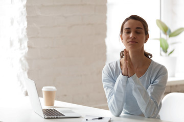 Businesswoman put hands together in prayer, meditating, relaxing sitting at workplace with closed...