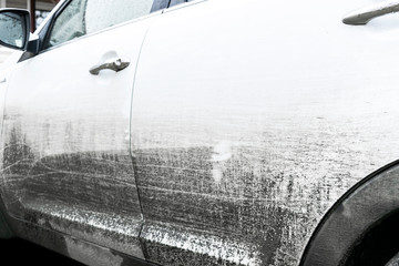 Side view of a very dirty car. Fragment of a dirty SUV. Dirty headlights, wheel and bumper of the off-road car with swamp splashes on a side panel