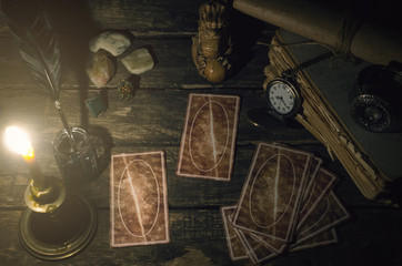 Tarot cards on fortune teller table in the lights of burning candle background. Futune reading concept. Divination.