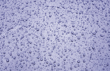 Water drops on car surface in blue tone.