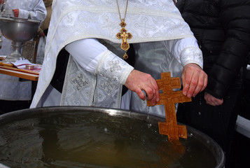 An Orthodox priest sanctifies the water on the cross on the day of baptism