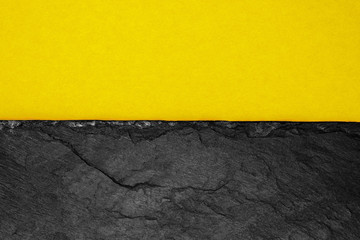 Abstract background composition of divided in the half matt dark yellow color paper and black stone...