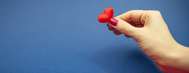 A girl holds one heart on a blue background. Valentine's Day and March 8
