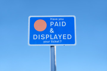 Paid and displayed car park sign against blue sky