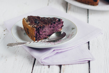 Homemade blueberry pie on a white wooden table next to a vase of