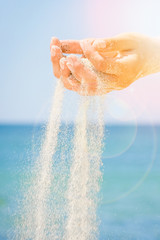 hands are pouring sand by the sea
