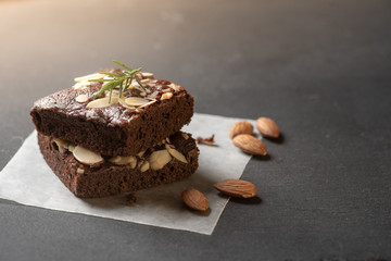 Homemade dark chocolate brownies topping with almond slices stacked on dark plate with copy space. Delicious bitter sweet and fudge. Brownie is one type of chocolate cake.