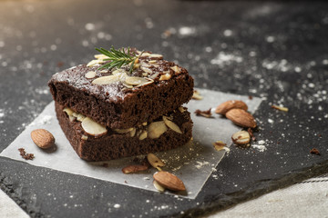 Homemade dark chocolate brownies topping with almond slices stacked on dark plate with copy space. Delicious bitter sweet and fudge. Brownie is one type of chocolate cake.