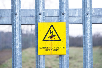 Danger of death safety sign on wooden telegraph post against blue sky