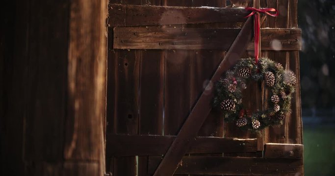 Snow gently falling on rustic barn with christmas wreath. Rustic Christmas scenes while testing out the blackmagic pocket cinema camera 4k