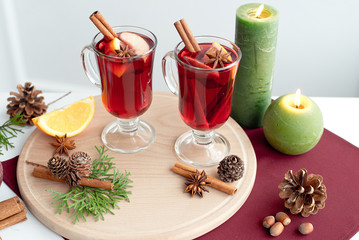 Christmas mulled wine with winter spices, green candles, wooden board on marsal napkin