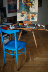 Artist's studio with a painting on an easel and a blue chair