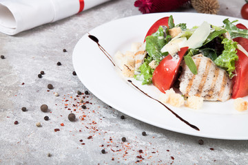 Close up view on Caesar salad on a concrete background with spices. Helthy food of American cuisine with free copy space for logo, text or brand. Picture for recipe. Flat lay lunch. 
