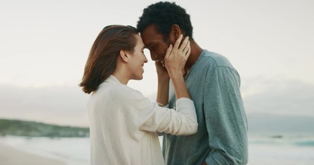 Happy young couple embracing and kissing on tropical beach at sunset - Powered by Adobe