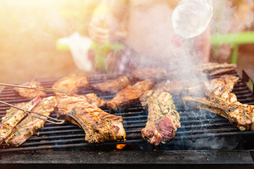 Friends frying the meat ribs and steaks, process close up. Barbecue on open air, weekend rest