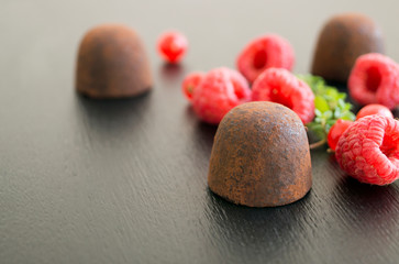 Candy truffles on black background with raspberry.