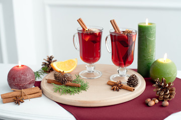 Mulled wine flavored with spices in glass and oranges